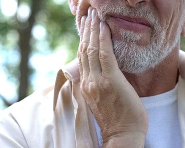 a man holding his cheek due to failed dental implant