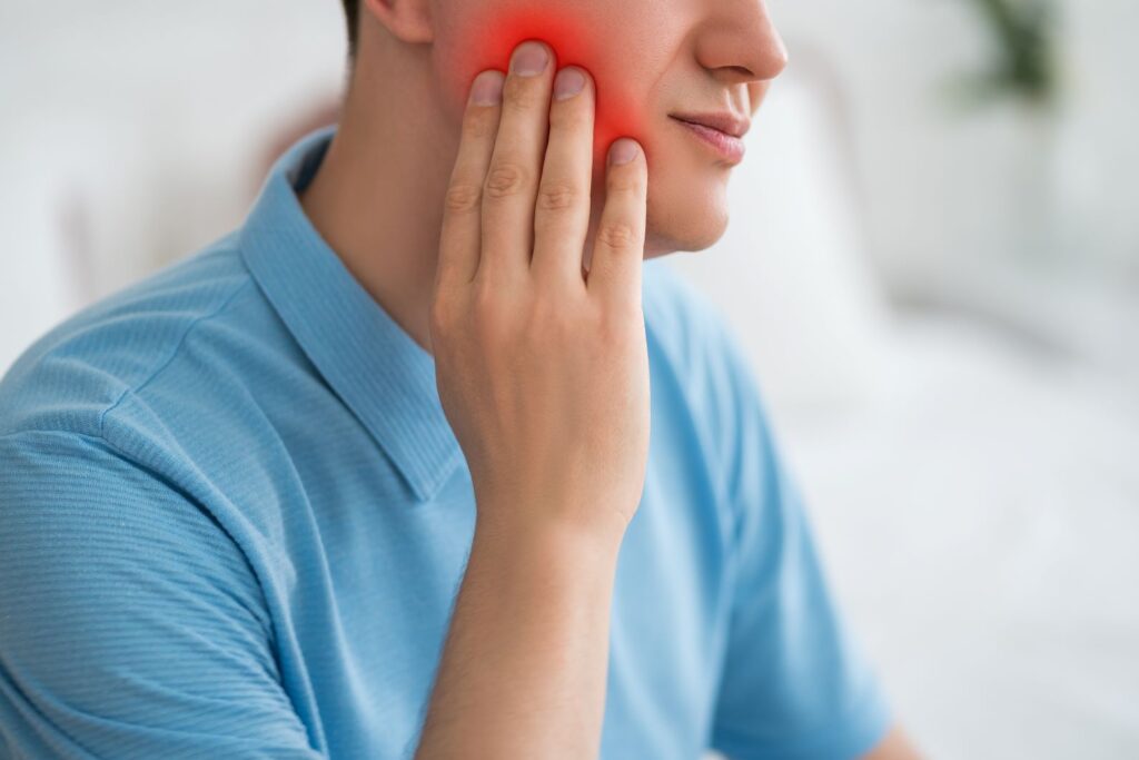 A young man holding his jaw from wisdom tooth pain.